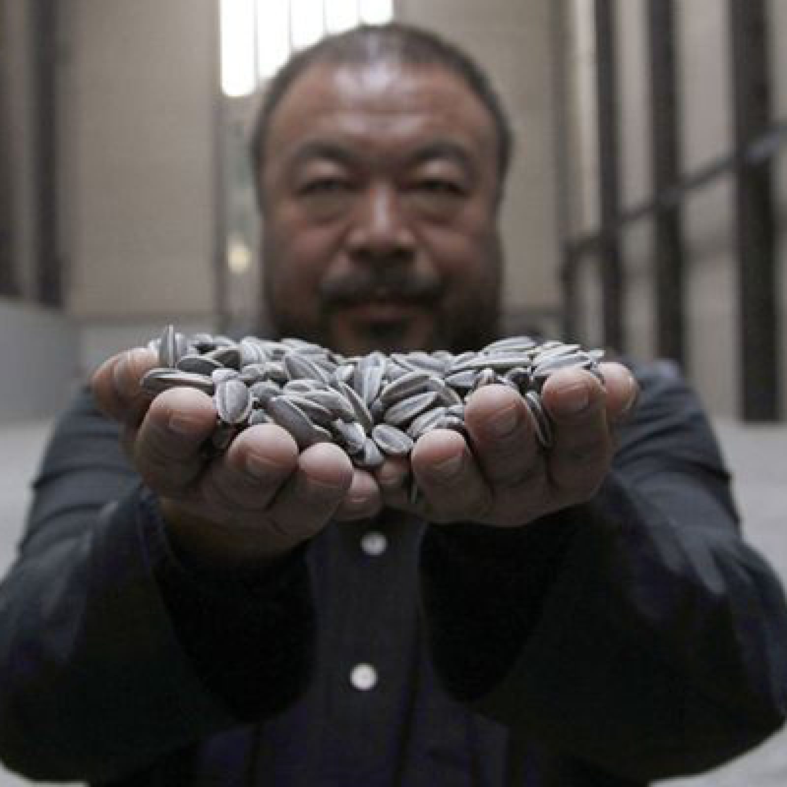 Chinese artist Ai Weiwei poses for a photograph with his new installation entitled 'Sunflower Seeds', at its unveiling in the Turbine Hall at the Tate Modern gallery, in London October 11, 2010. REUTERS/Stefan Wermuth (BRITAIN - Tags: ENTERTAINMENT)