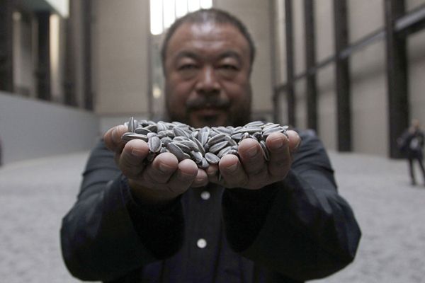 Chinese artist Ai Weiwei poses for a photograph with his new installation entitled 'Sunflower Seeds', at its unveiling in the Turbine Hall at the Tate Modern gallery, in London October 11, 2010. REUTERS/Stefan Wermuth (BRITAIN - Tags: ENTERTAINMENT)