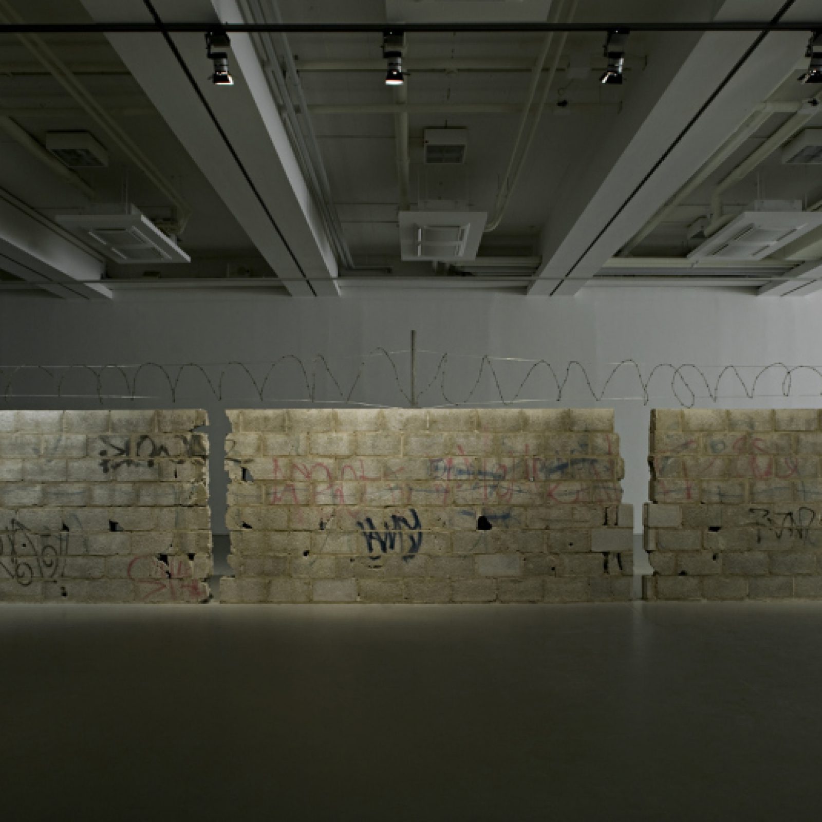 Teresa Margolles, Muro Ciudad Juárez, 2010, bloques de concreto, alambre de púas y agujeros de armas resultado de un tiroteo vengativo vinculado al crimen organizado en Ciudad Juárez, México. Colección Frac Grand Large – Hauts-de-France, Dunkerque. Vista de la instalación en la exhibición Teresa Margolles: Frontera, Fridericianum, Kassel, Alemania, 2010. Foto: Nils Klinger. Cortesía de la artista y Galerie Peter Kilchmann, Zurich