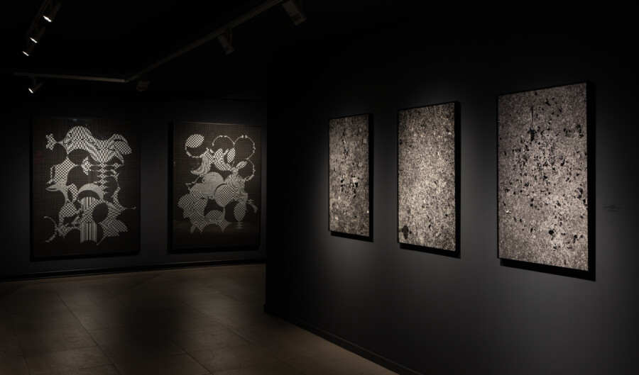 una serie de dibujos en gran formato de retículas en blanco y negro sobre una pared negra de fondo