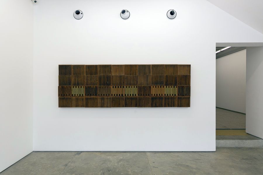 obra del artista hondureño Adán Vallecillo que consiste en cajas de puros (tabacos) formando un rectángulo color marrón colocado sobre una pared blanca